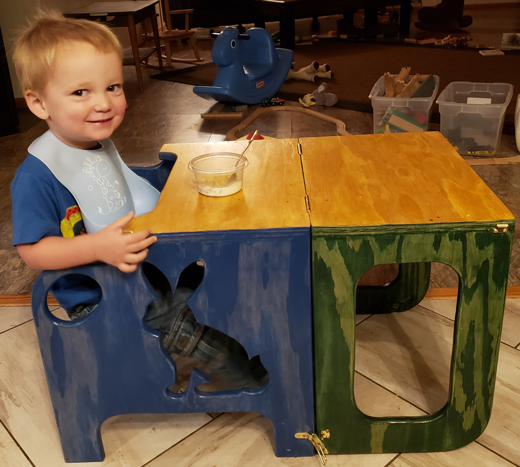 a very happy toddler sitting at a kid-sized table