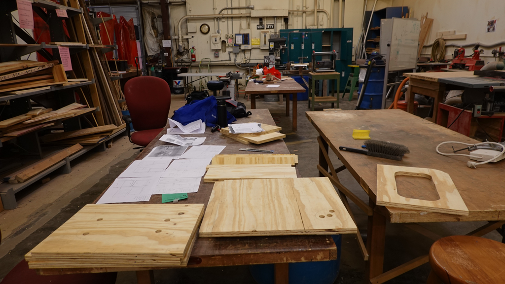 the woodshop at a makerspace with cutout pieces of plywood on a table in the foreground