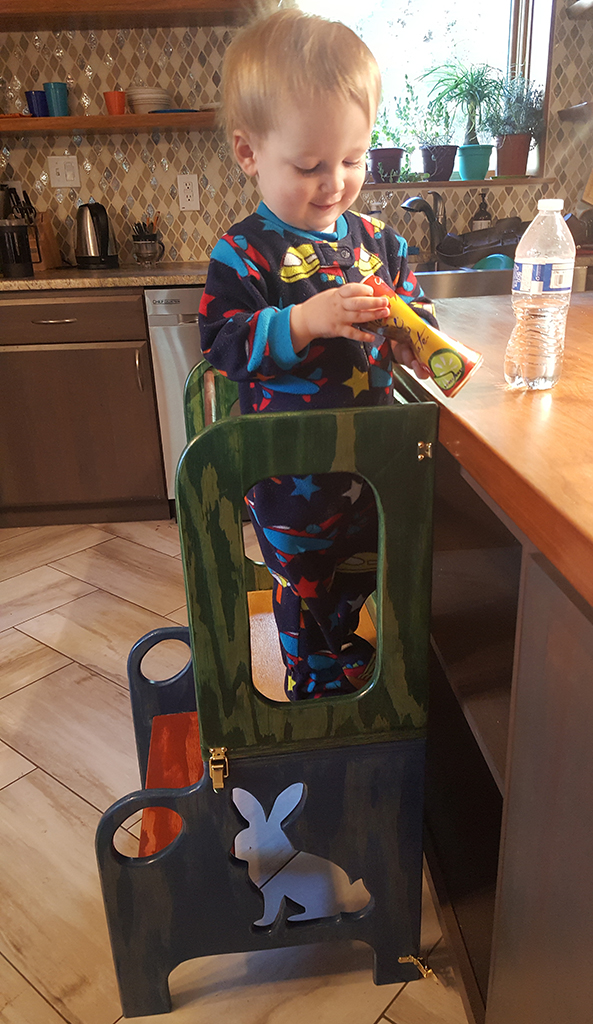 a very happy toddler on a colorful step stool